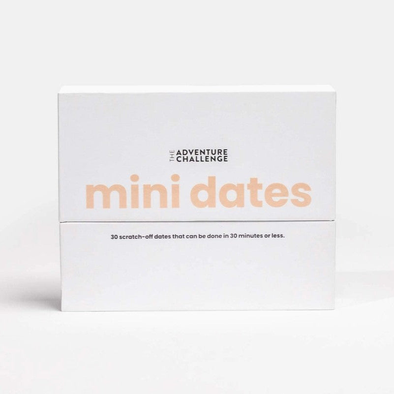 Mini Dates is a white box, likely made of cardboard or similar material, split horizontally into two sections. On the top section, it features the words "THE ADVENTURE CHALLENGE" in small, dark letters at the top, and below, the phrase "mini dates" in a large, soft coral color font, which dominates the visual space. The bottom section includes the text "30 scratch-off dates that can be done in 30 minutes or less." in a smaller, dark font.