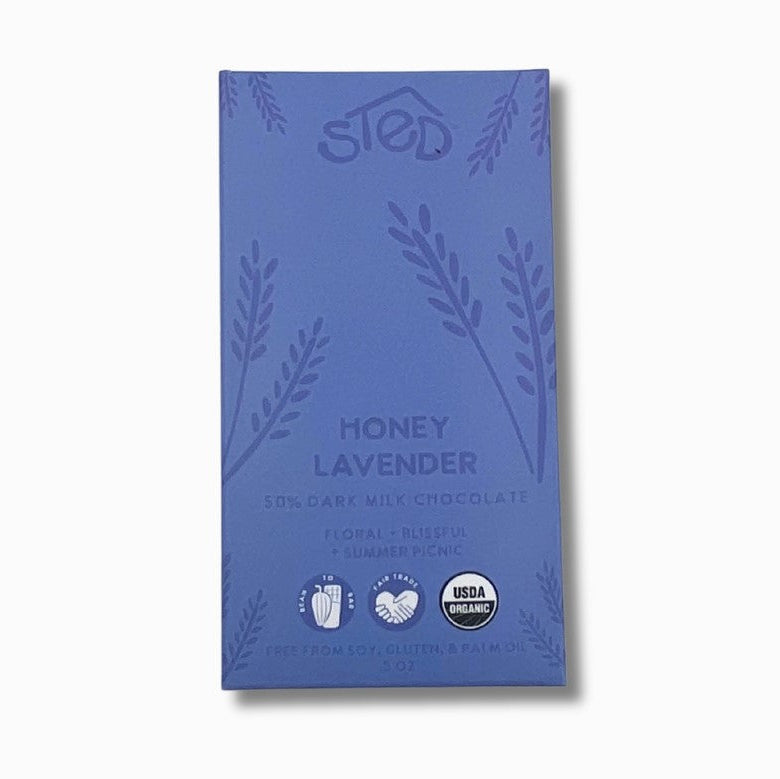 Mini honey lavender dark chocolate bar in its blue rectangular package is featured with purple lettering and details on a white background. 