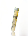 A clear glass test tube with a silver metal screw cap, filled with pale yellow liquid and labeled 'Mango Pellin' cocktail mix, photographed on a clean white background with a faint reflection below.