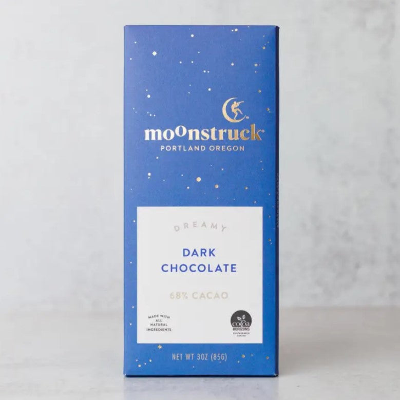 Moonstruck dreamy dark chocolate in its blue rectangular package in gold lettering and gold spots, white label gray and blue words in the label on a marble like background. 