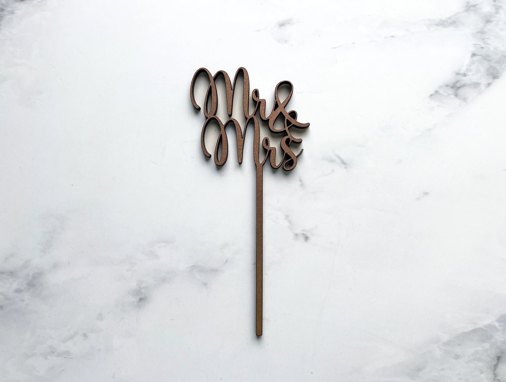 Mr & Mrs wooden cake topper featured in a marble-like background. 