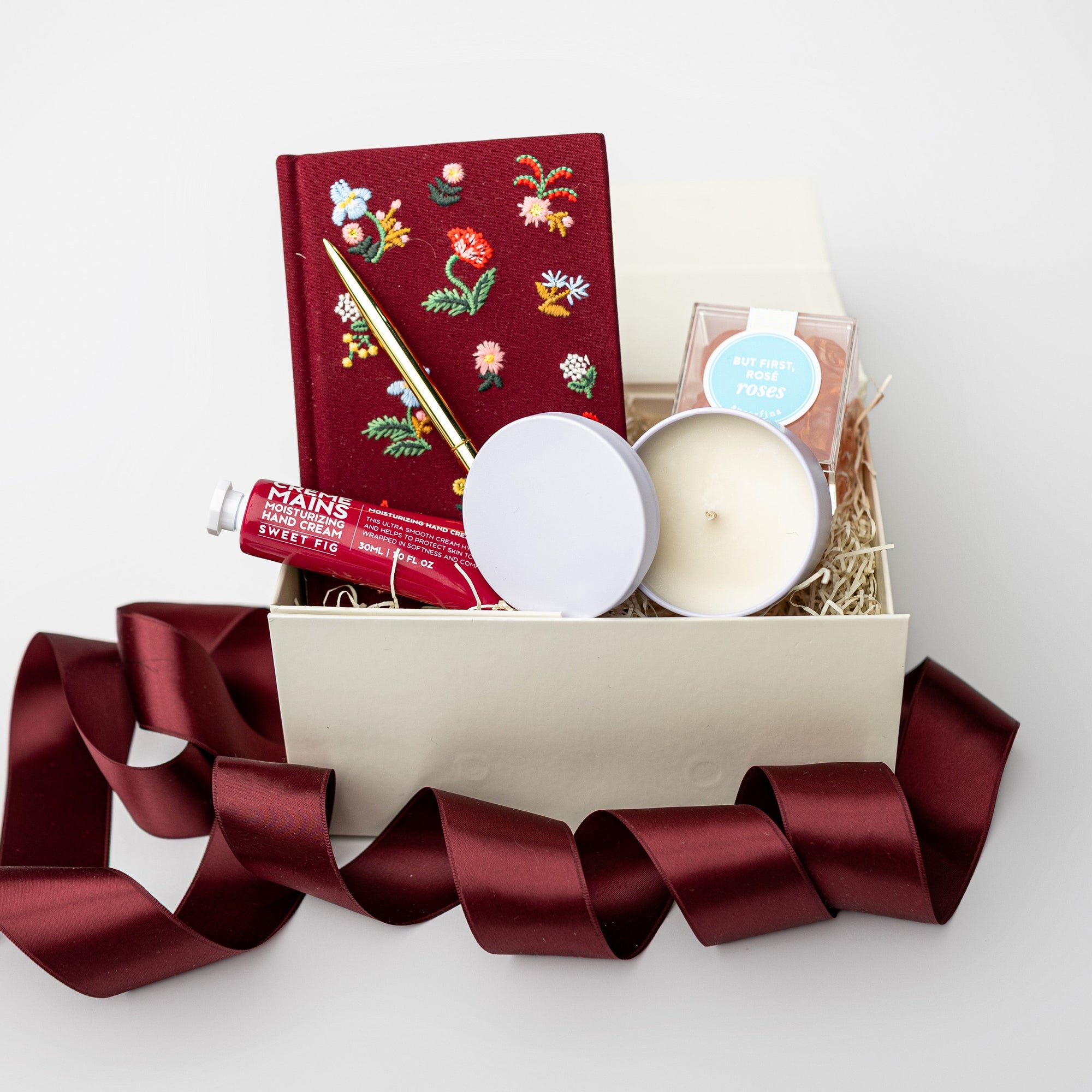 Gift box with candles, a book, and other items on a white background