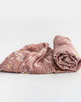 Muslin daises swaddle blanket featured pink with daisy flowers on a white background.