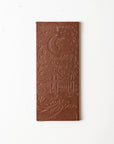 Nutty milk chocolate cinnamon bar is featured unwrapped showing the bar that has details on it on a white background. 