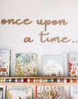 Once upon a time wooden wall cut out is featured in alder wood on top of a children's book in a bookshelf on a white background.