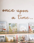 Once upon a time wooden wall cut out is featured in alder wood on top of a children's book in a bookshelf on a white background.