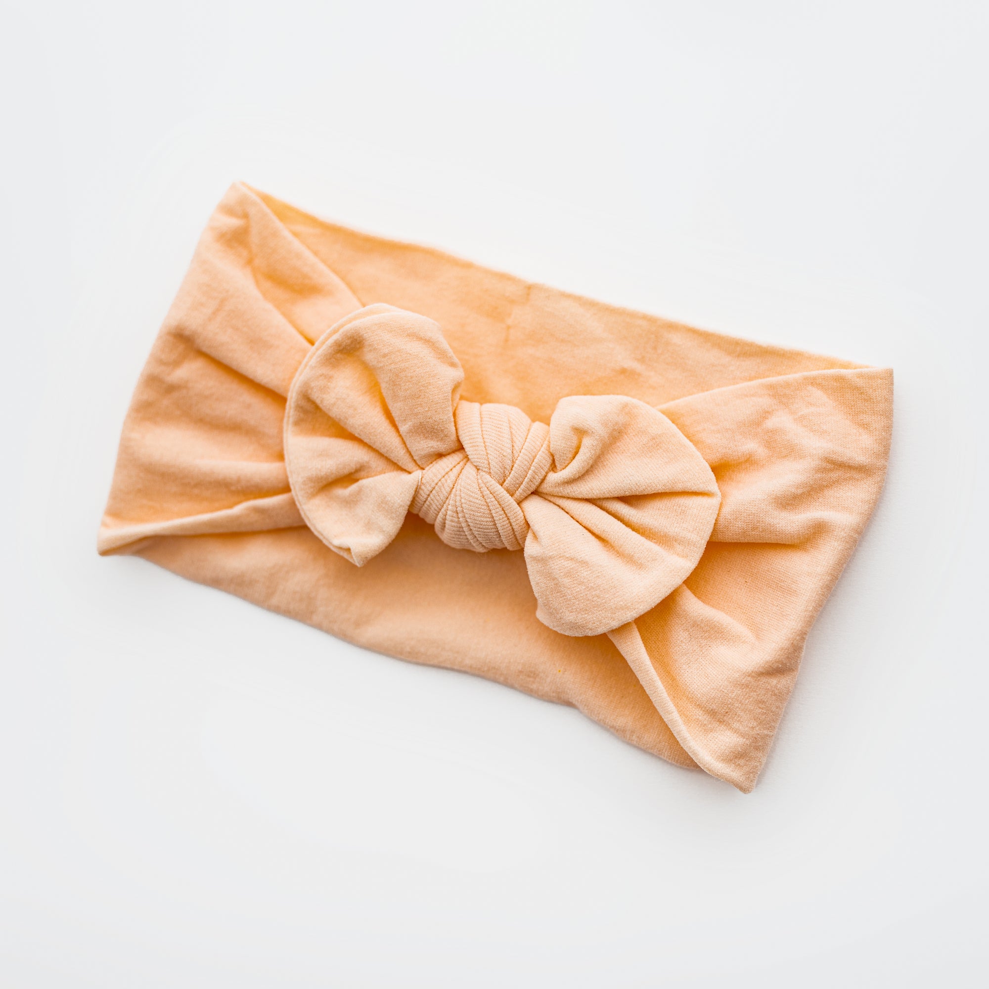 Orange baby headband is featured on a white background. 