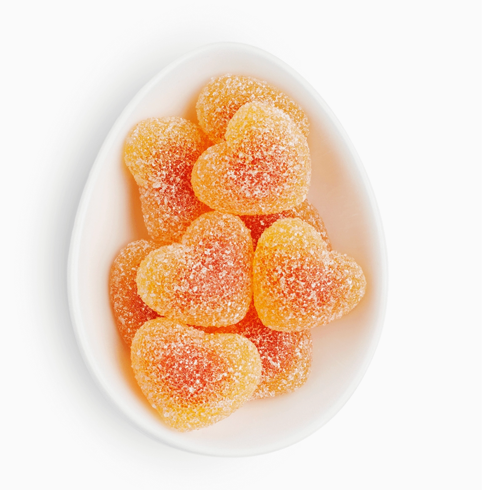 Sugarfina Peach Bellini Gummies in a white tray, showing peach-colored gummy candies inside, each shaped like miniature heart. On a white background. 