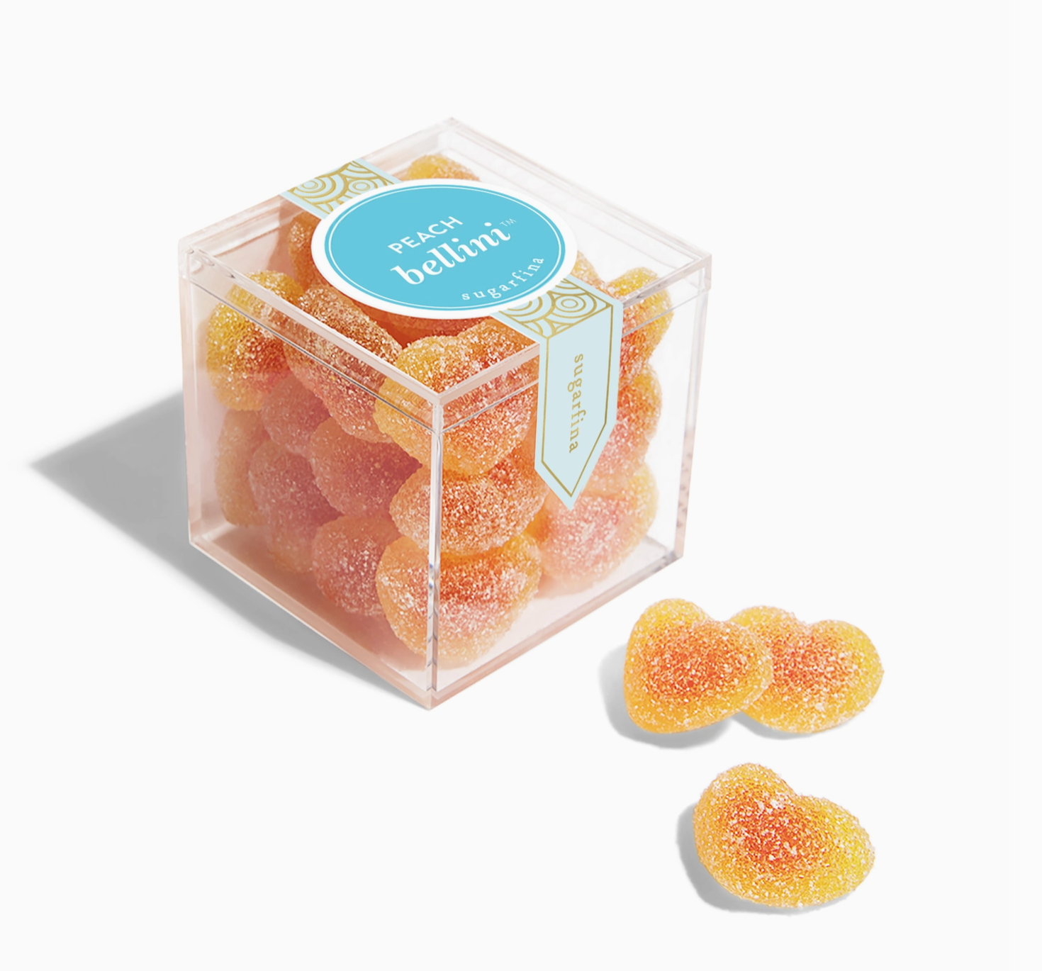 Sugarfina Peach Bellini Gummies in a clear plastic cube-shaped package, showing peach-colored gummy candies inside, each shaped like miniature hearts, with the Sugarfina logo and 'Peach Bellini' label on the front. Three outside on a white background. 