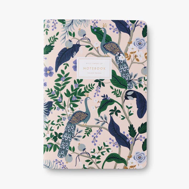 Peacock notebook one, pink with peacock illustration with white label and gold lettering on white background.