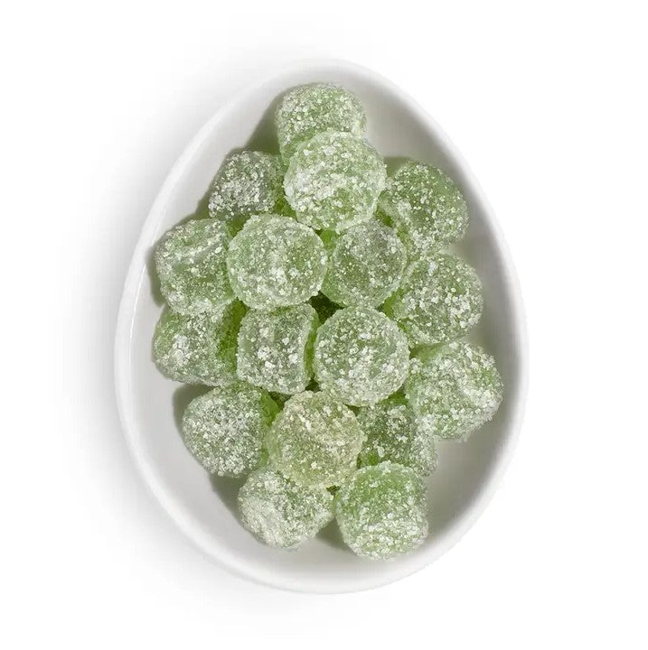 Pear italian ice gummies from Sugarfina are featured several of them in round and green colored in a ceramic white dish on a white background.  