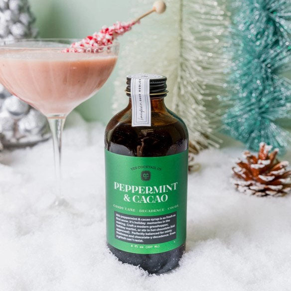 Brown jar with green label with white letters. Peppermint and Cacao syrup from Yes Cocktails with Christmas background.