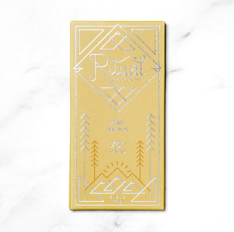 Ritual Peru chocolate bar in its yellow rectangular shaped package in silver lettering and dark yellow details on a marble like background. 