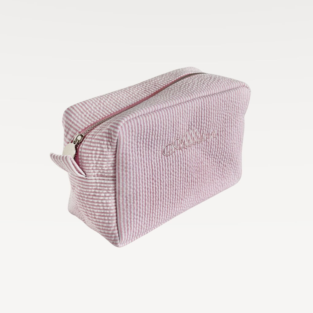Pink textured toiletry bag with a zipper on a white background