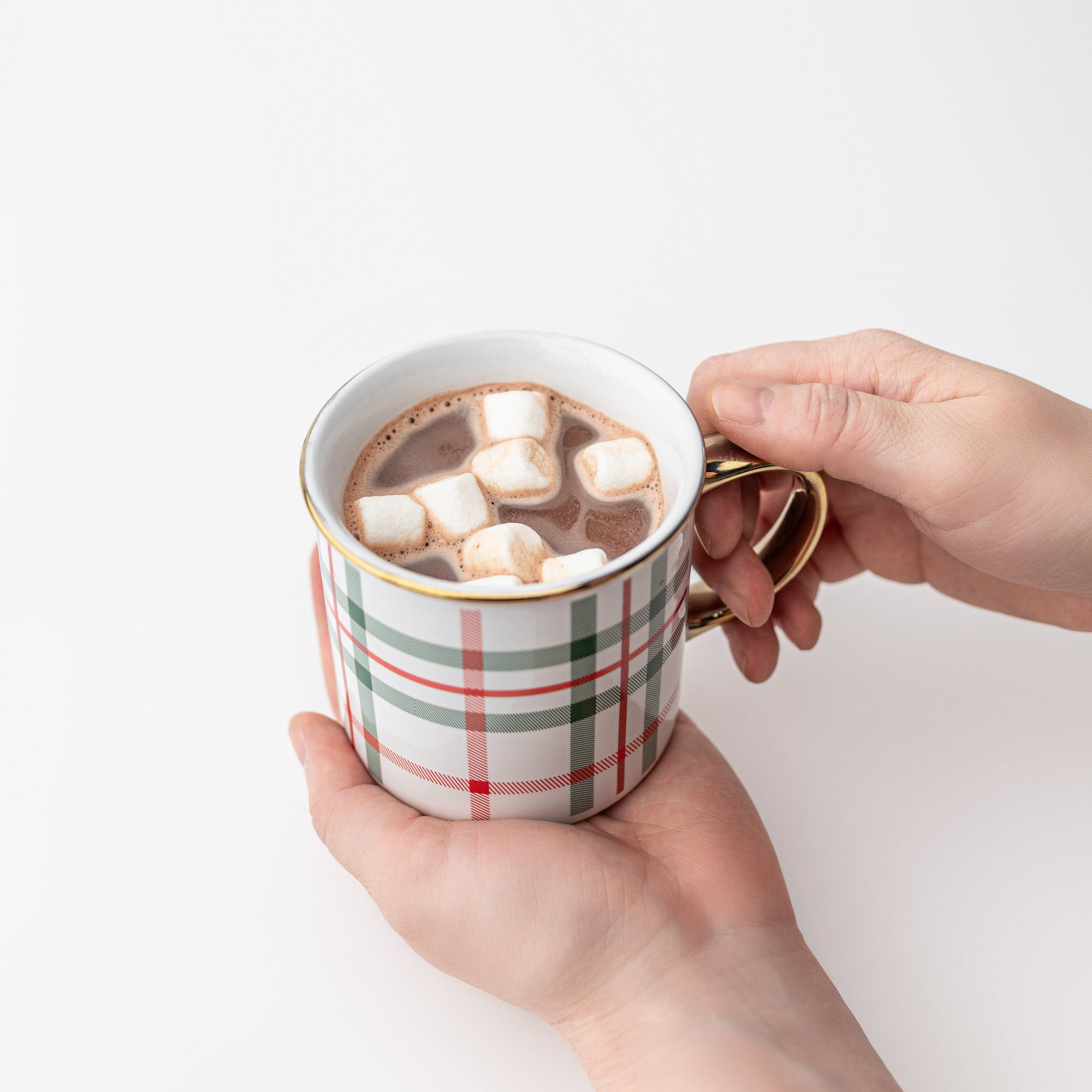 Our signature plaid mug gold rim and handle featured being held with chocolate and marshmallows inside on a white background.