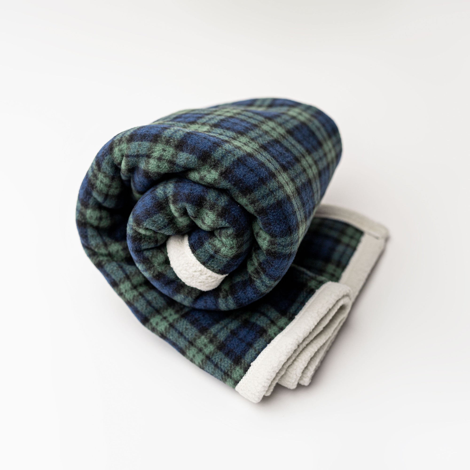 Plaid throw blanket is featured with its blue and green grid and white edges on a white background. 