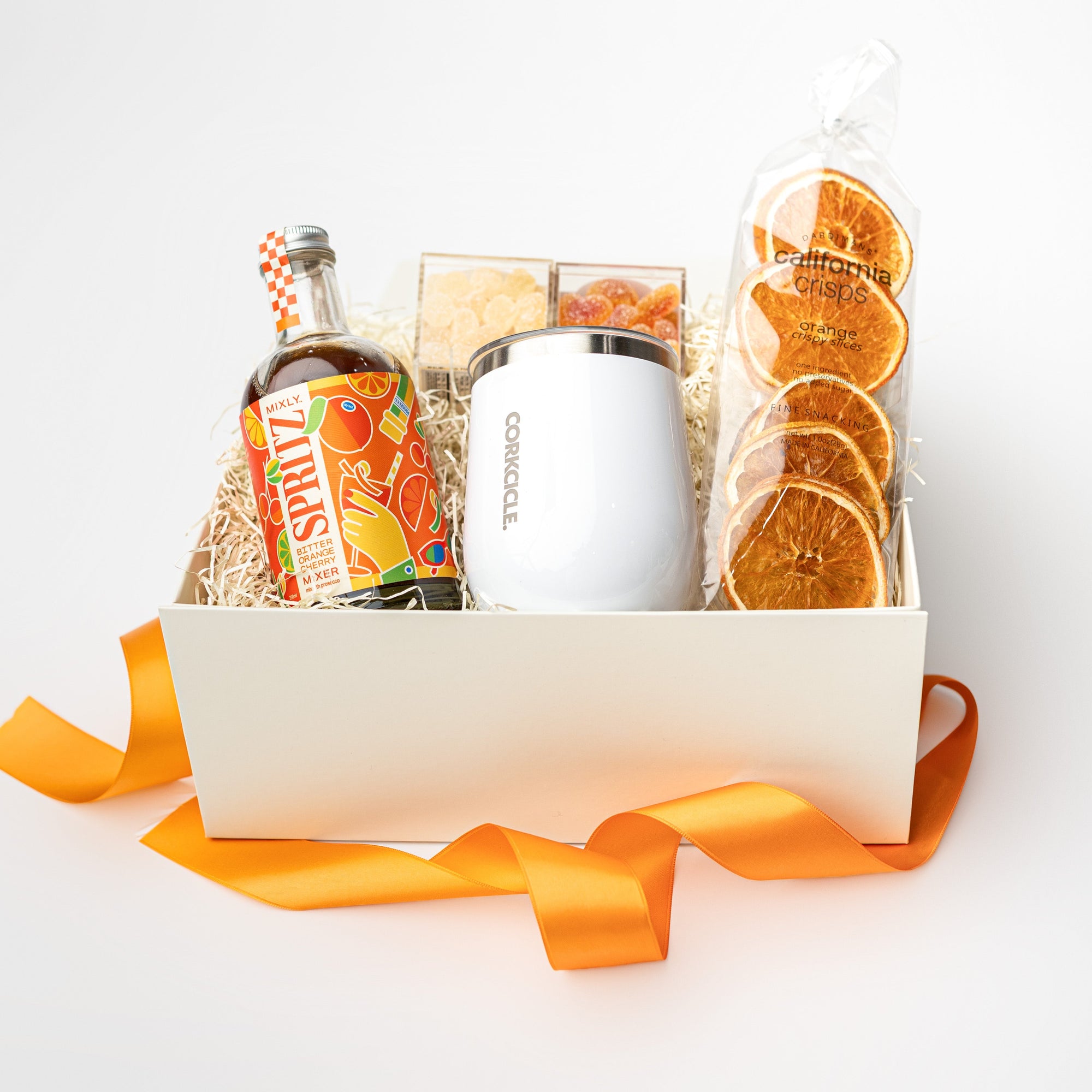 Gift basket with a bottle of cocktail mix, oranges, and a box on a white background