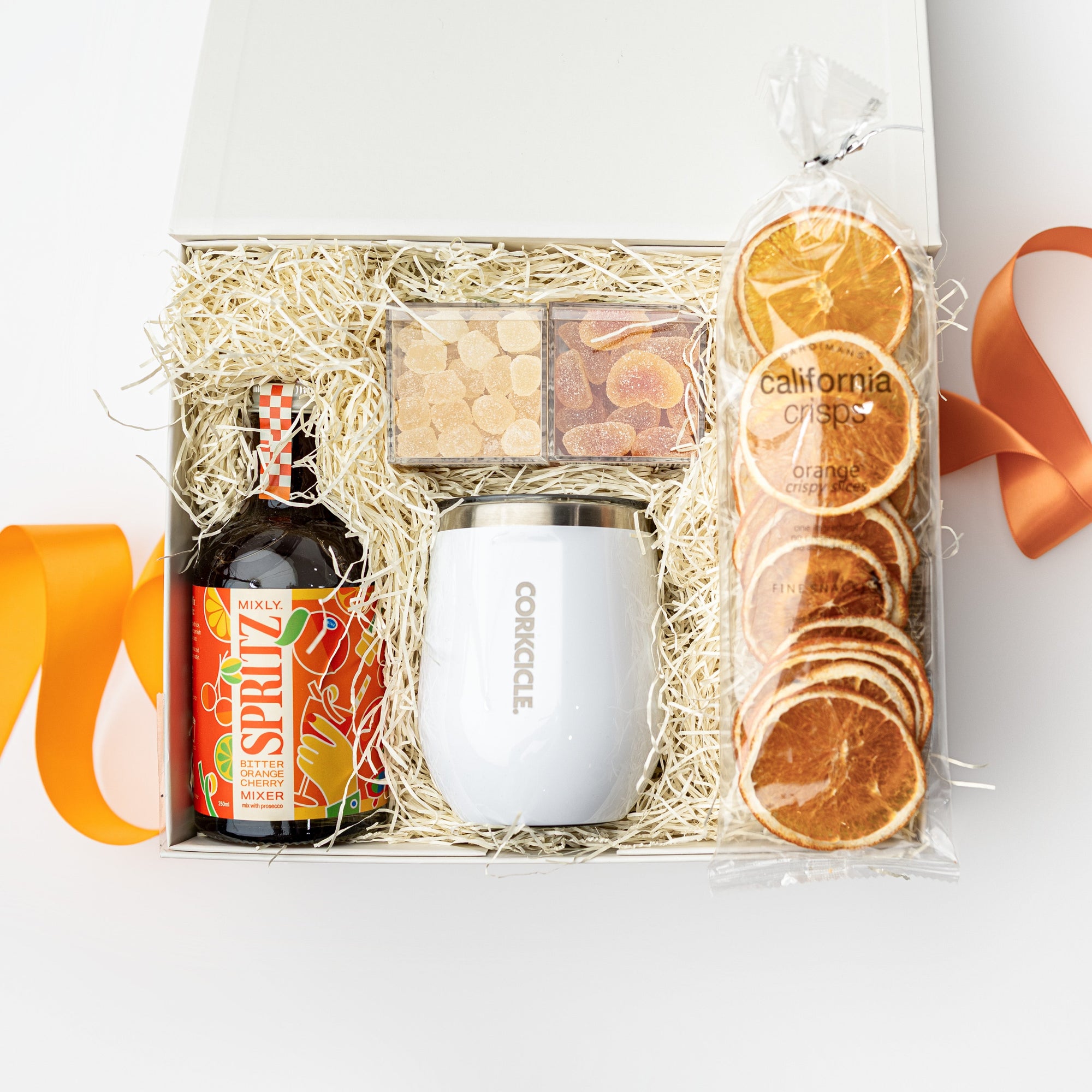 Gift basket with a bottle, mug, and orange slices on a white background