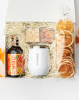 Gift basket with a bottle, mug, and orange slices on a white background