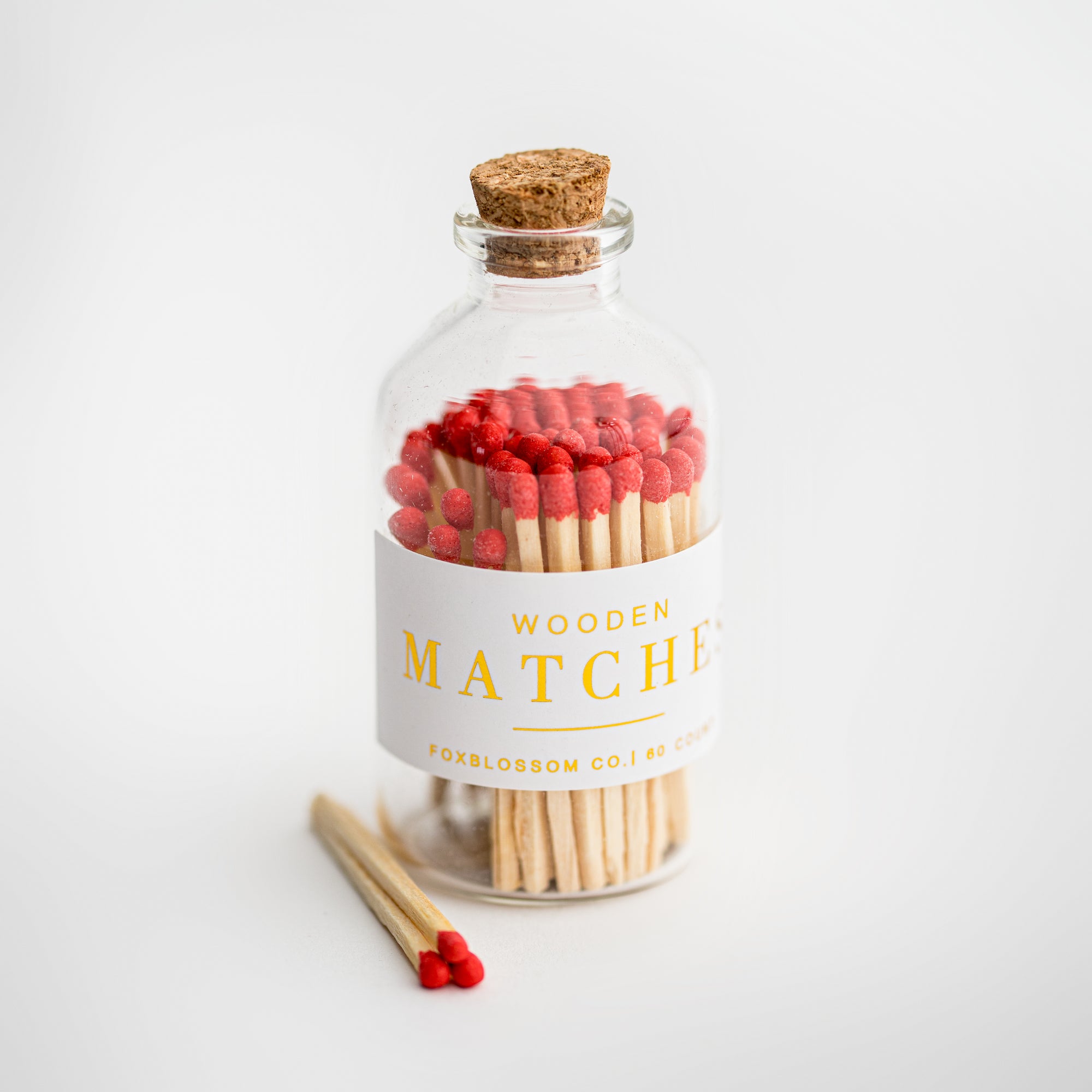 Wooden Red Matches, clear jar with wooden matches with red tip, white label with gold lettering, and wood cork. 