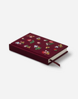 Maroon notebook with floral patterns on a white background
