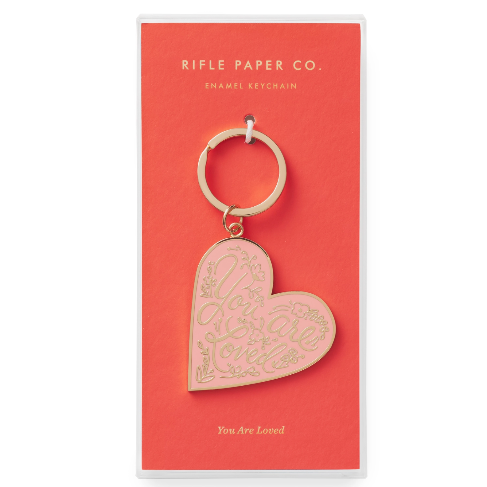 Heart-shaped enamel keychain with a soft pink background and gold lettering that reads ‘You Are Loved,’ attached to a gold key ring.