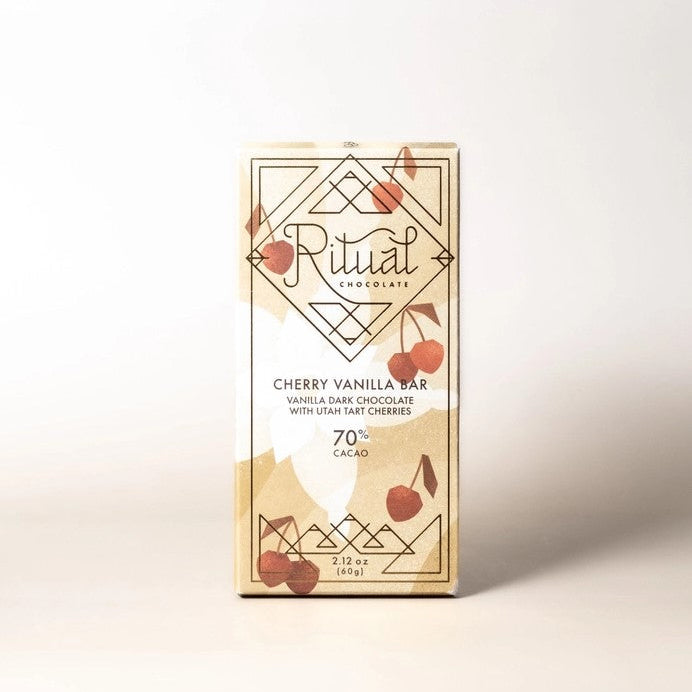 Ritual cherry vanilla chocolate bar featured in its rectangular-shaped package with an illustration cherries yellow background vanilla flower and black lettering on a white background. 