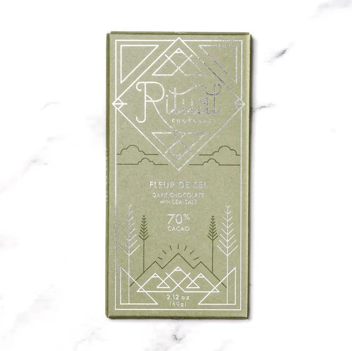 Ritual fleur de sel chocolate bar is featured in its green rectangular shaped package with silver lettering and dark green details on a marble liked background. 
