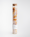 Rose bath salts are featured in a transparent tube container with corch lid and a white label with black lettering. 