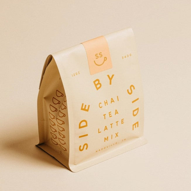 Side by side chai tea latte mix is featured in its beige package with orange lettering on a beige background. 
