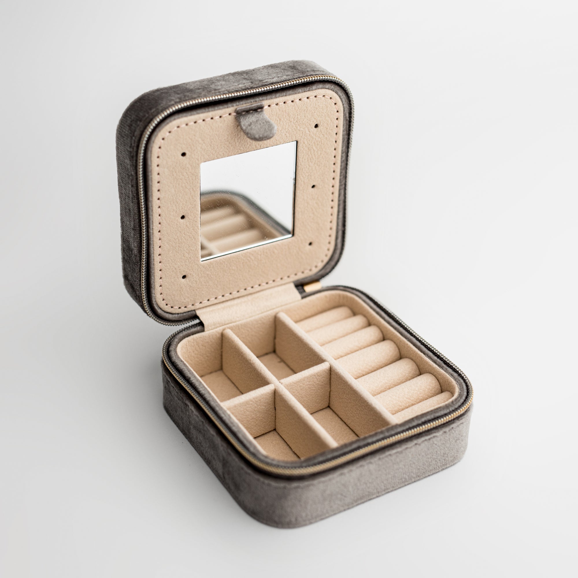 Silver velvet jewelry box, close-up photograph showcases a silver velvet jewelry box, opened to display its beige interior compartments and organizers, set against a clean white backdrop.