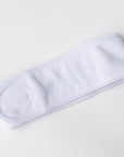 Plush white spa headband worn to keep hair away from face during skincare routine.