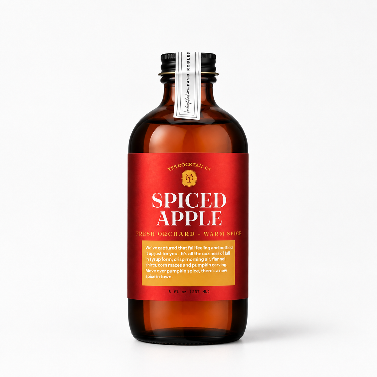 A bottle of Yes Cocktail Co. Spiced Apple Fresh Orchard - Warm Spice, featuring an amber glass bottle with a vibrant red label and a black cap, set against a clean white background.