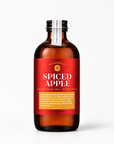 A bottle of Yes Cocktail Co. Spiced Apple Fresh Orchard - Warm Spice, featuring an amber glass bottle with a vibrant red label and a black cap, set against a clean white background.