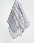 Stripped linen kitchen towel featured in its white and black lines design on a white background. 