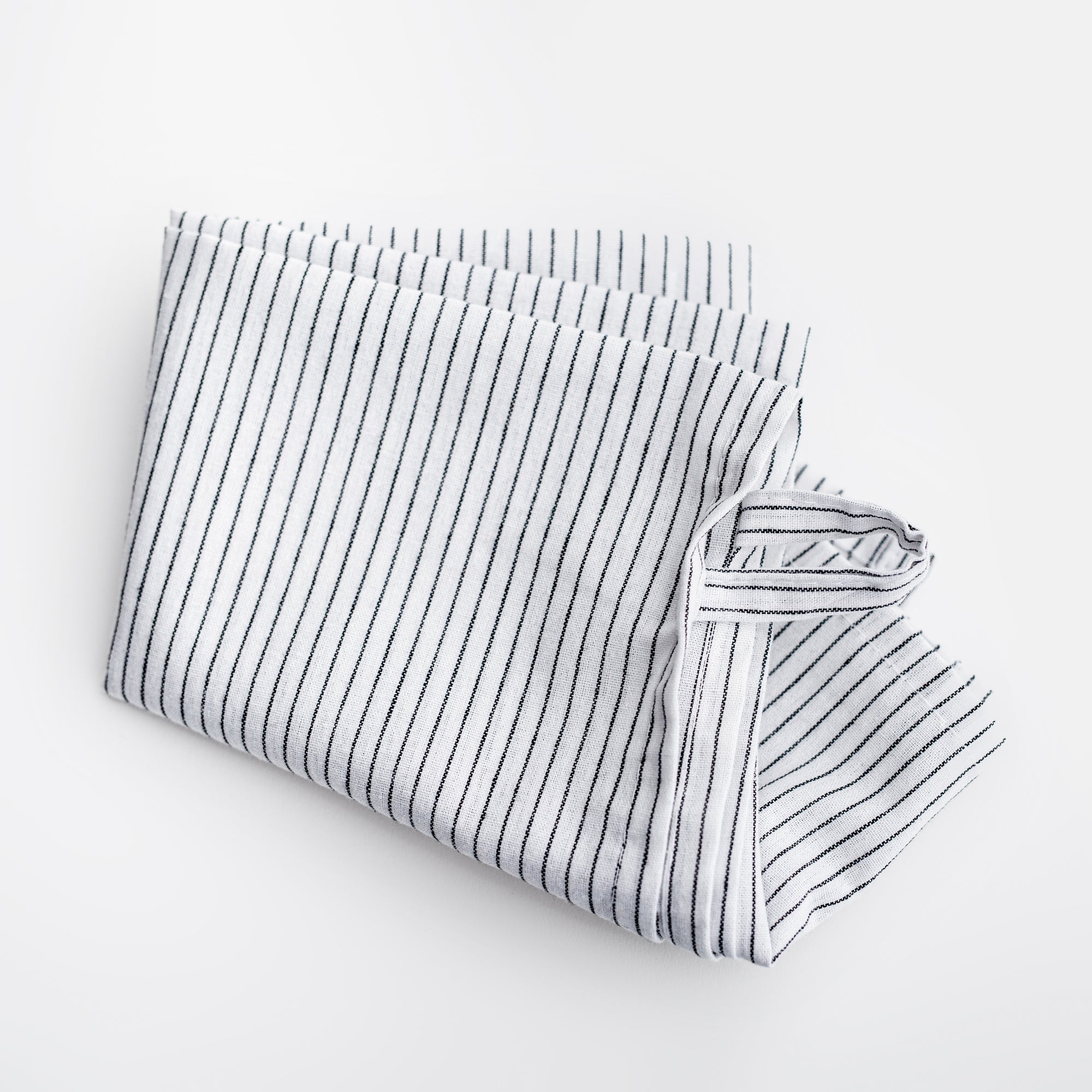 Stripped linen kitchen towel featured in its white and blackl lines design on a white background. 