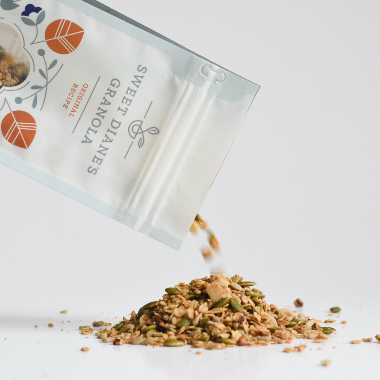 Sweet Dianes granola being poured from a packaging bag onto a white surface.