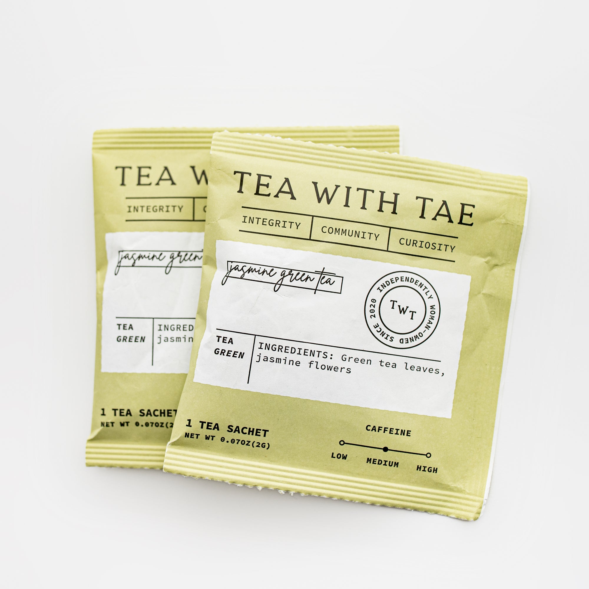 Two jasmine green sachets featured in their square packages with a white rectangular label with black lettering on a white background. 