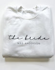 The bride's custom name sweatshirt in white, personalized in black lettering the bride Mrs. Anderson, in a white background