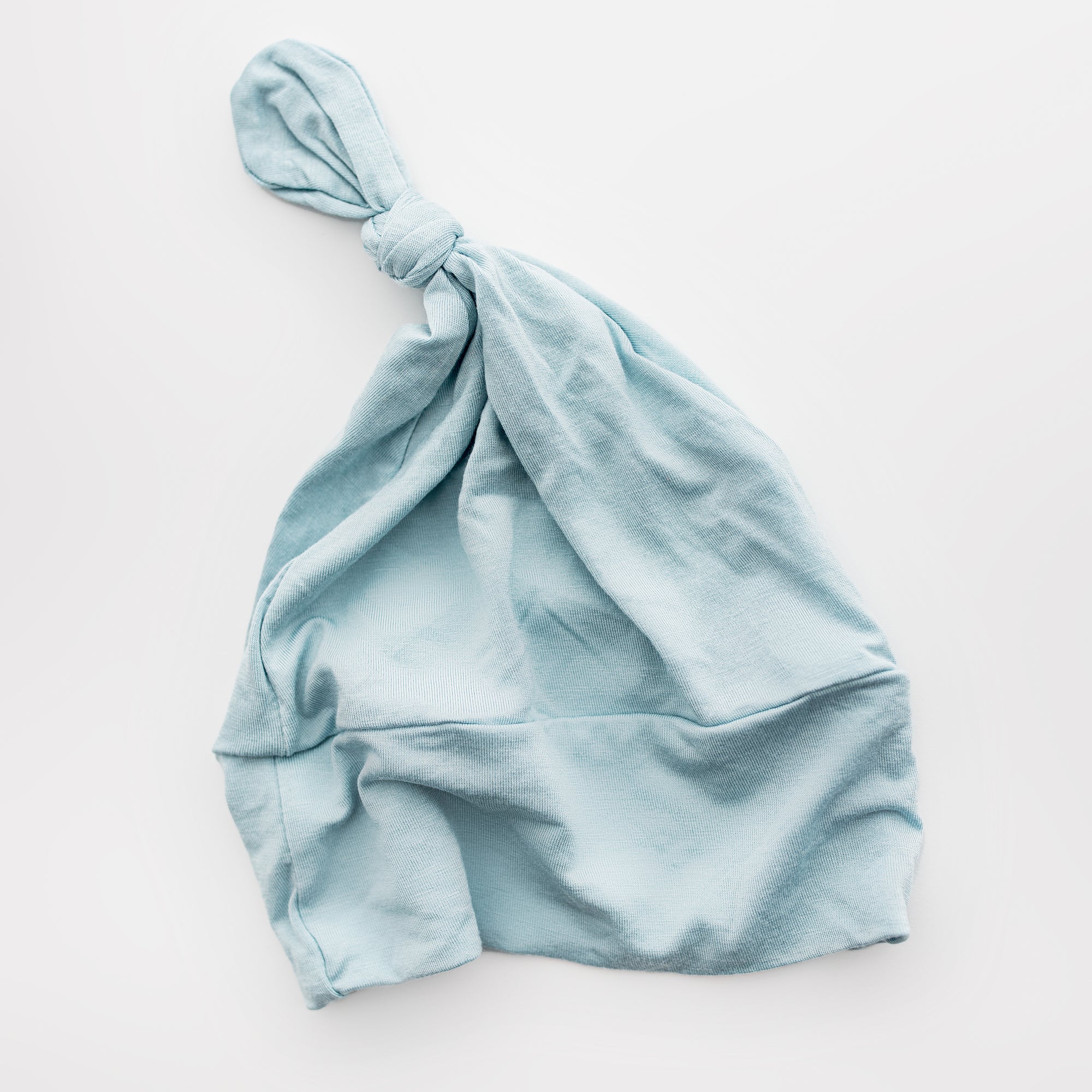 Top knot babu beanie is featured in blue color on a white background. 