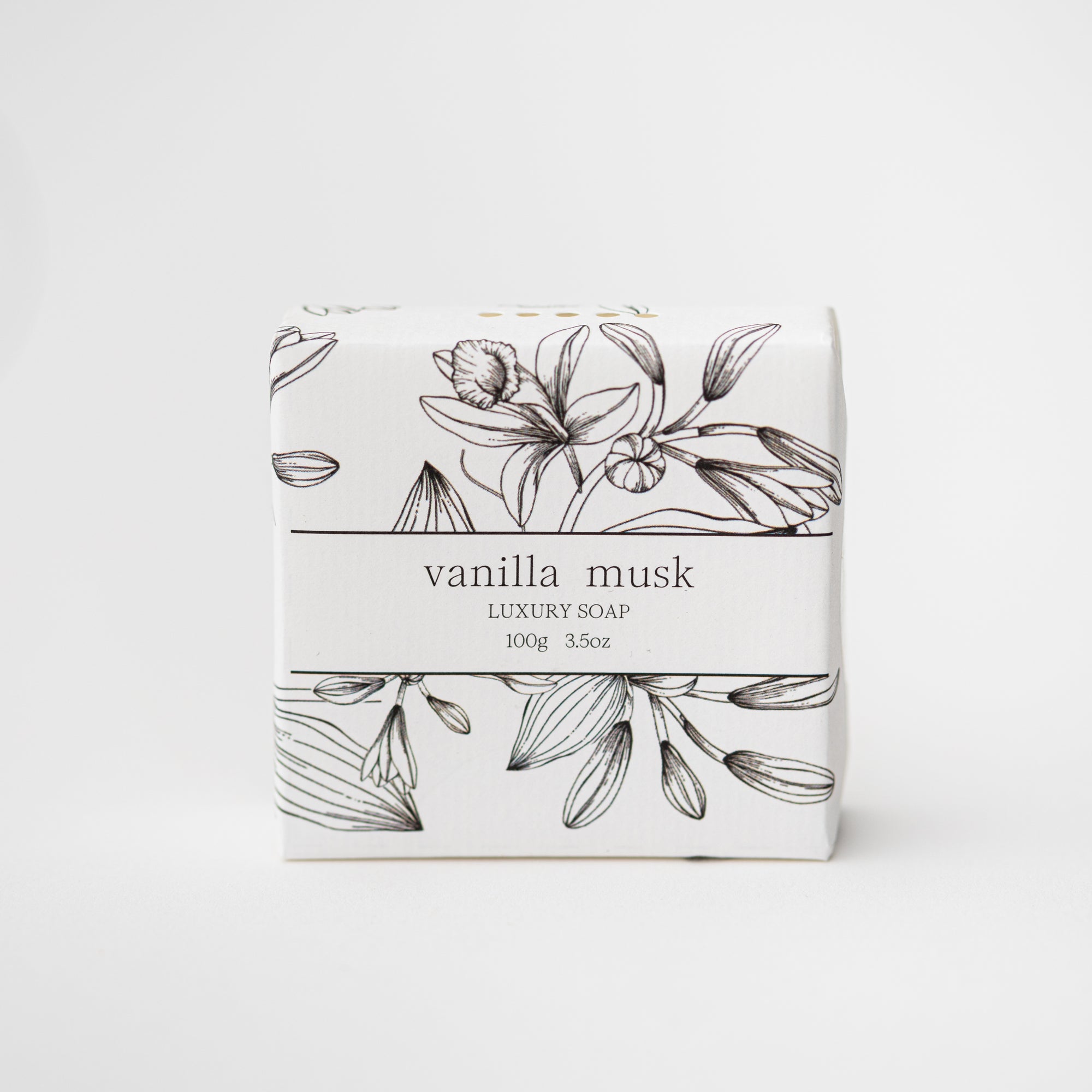 Vanilla Musk luxury soap is featured in its square-shaped container with floral illustrations in black and black lettering on a white background. 