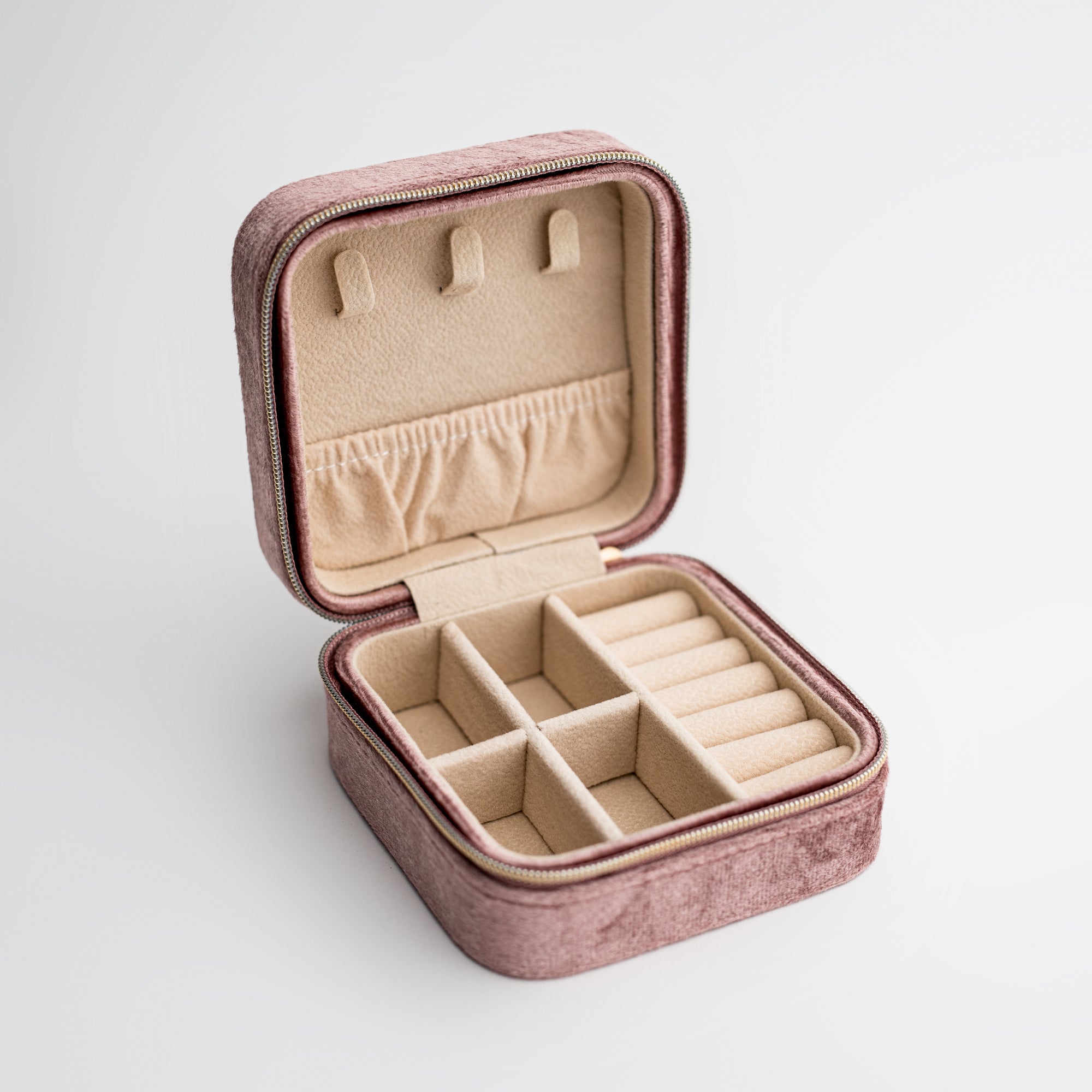 Velvet jewelry box in mauve color open with brown inside. 