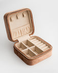 Showcased velvet jewelry box in taupe color open showing its division and light brown color in the inside on a white background. 