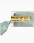 A packaged bridal emergency kit by Pinch Essentials, featuring a rolled sage green silk scarf inside a clear plastic box with a gold label that reads 'MINIMERGENCY KIT FOR BRIDESMAIDS' and a matching sage green ribbon tied to the side, on a white background.