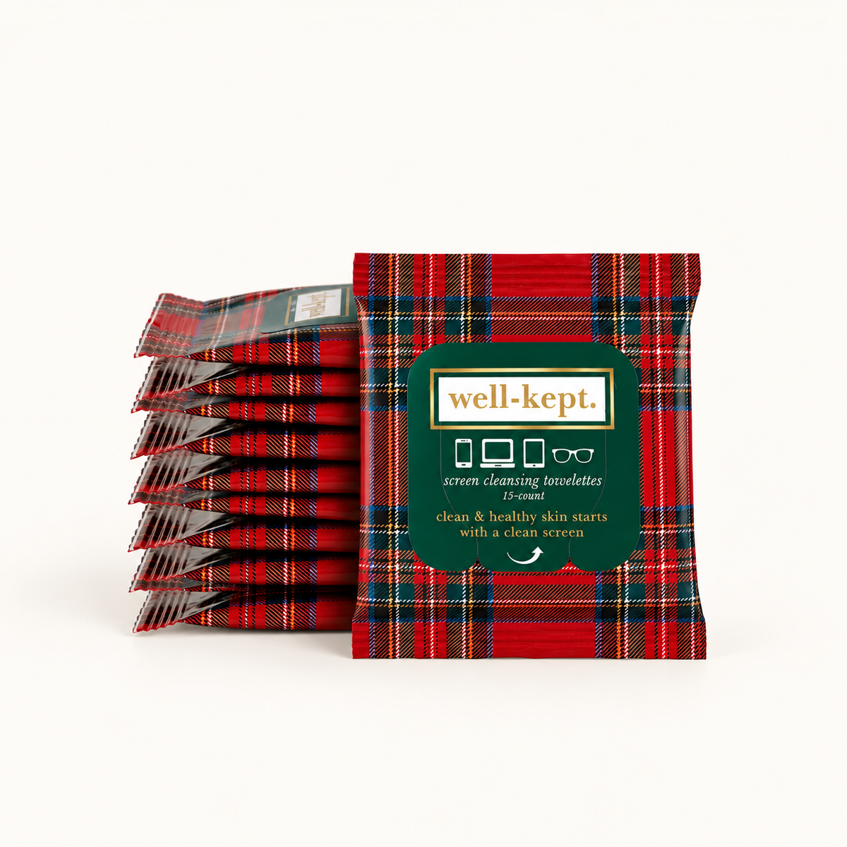 A stack of red tartan-patterned screen cleaning wipes stands in front of a single upright packet on a clean white background. The front packet has a dark green label with the brand name 'well-kept.