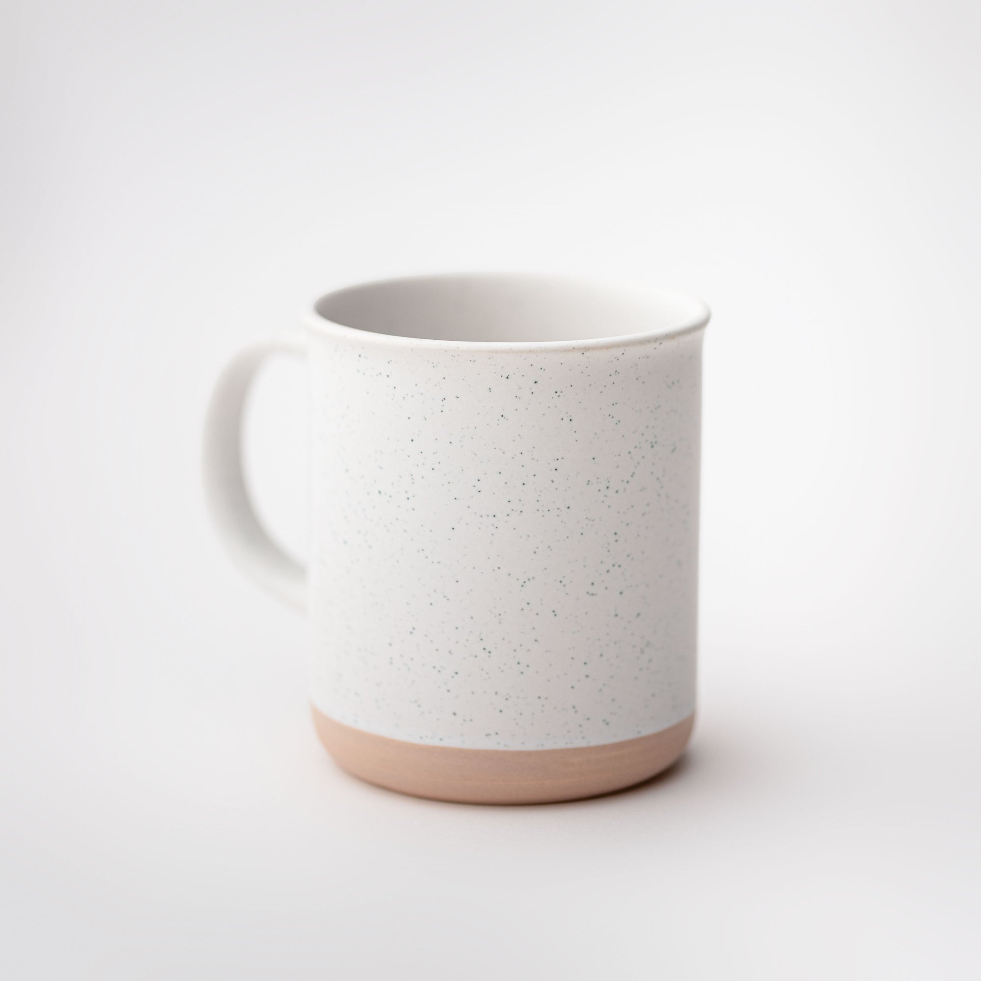 White ceramic mug stone-tan bottom with speckles featured on a white background.  