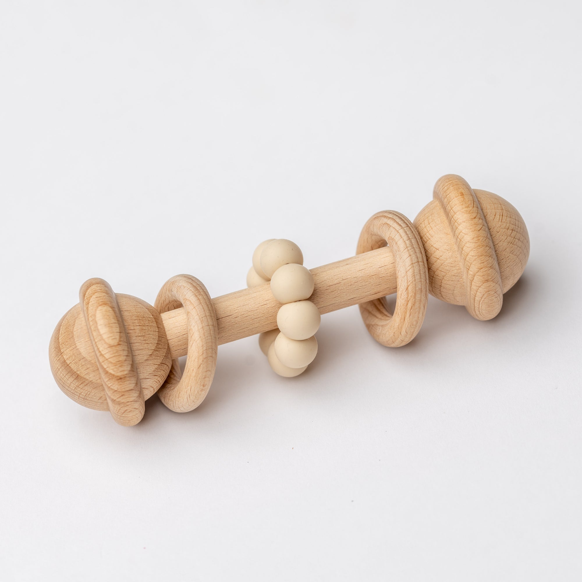 Eco-friendly wooden baby rattle with a natural maple wood ring and beige silicone teething beads, designed for infants to grasp and chew.