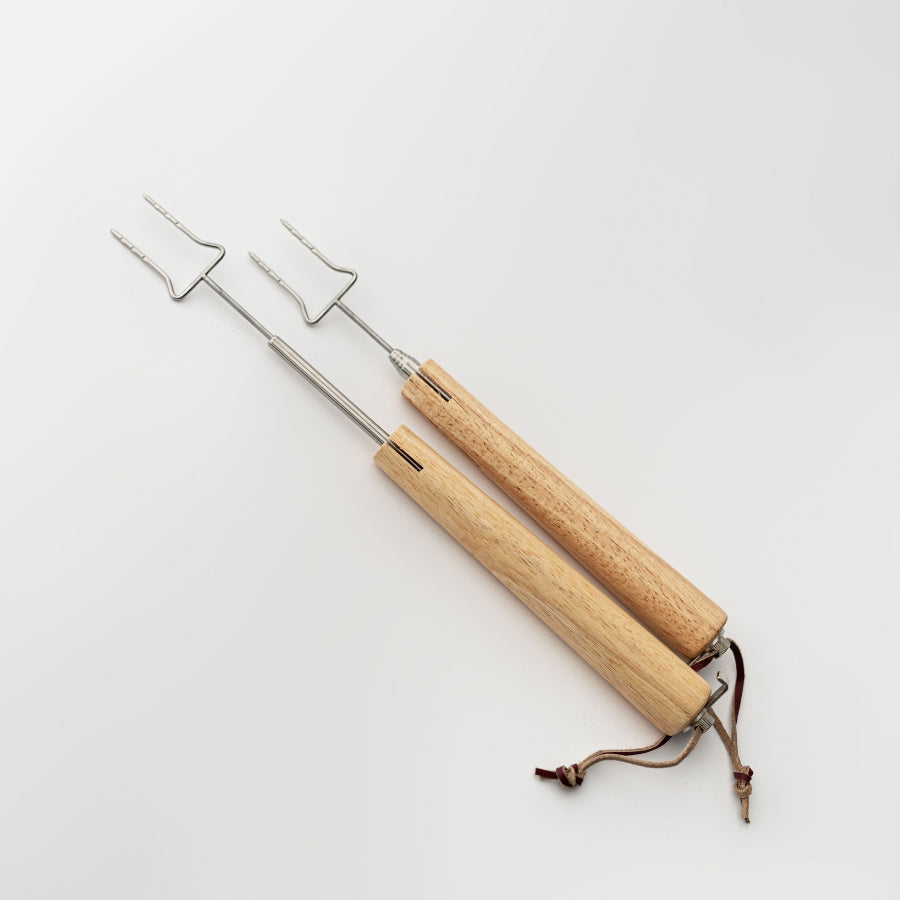 Two wooden skewers with metal prongs on a light gray background