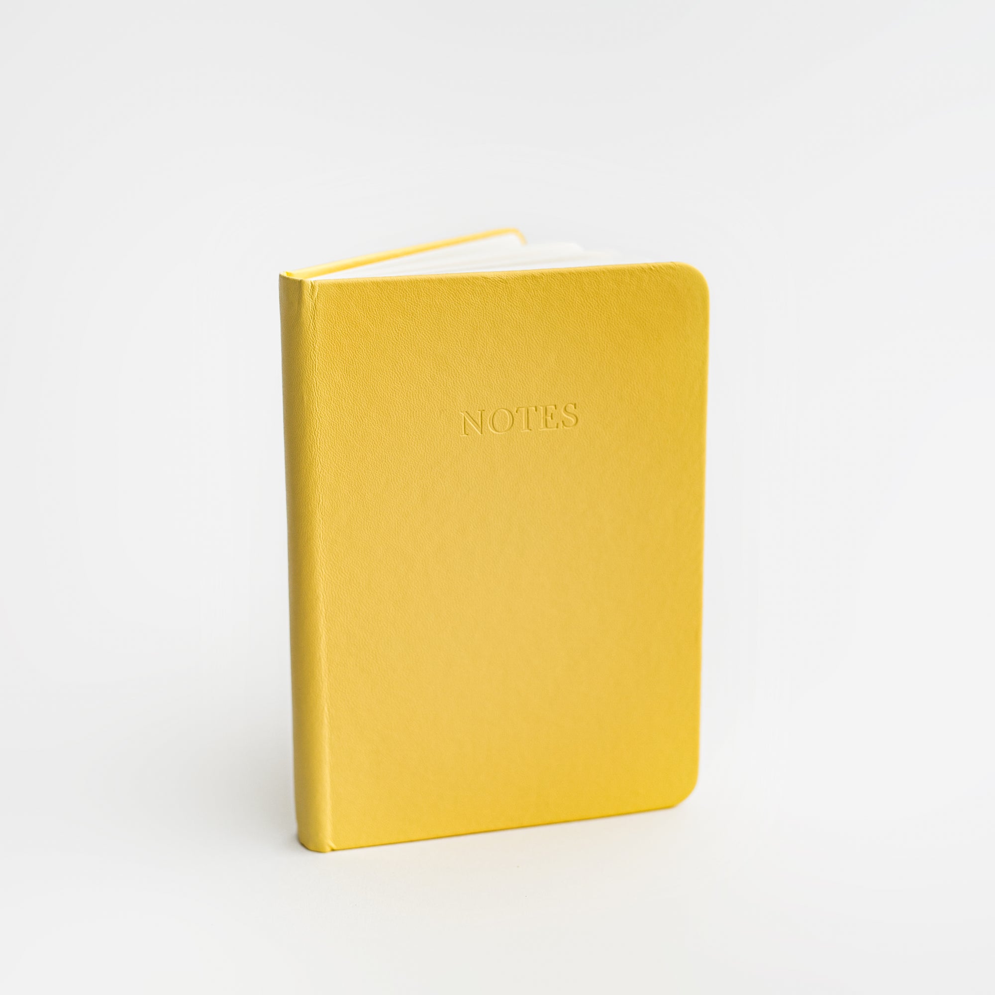 Yellow pocket softcover notebook featured on a white background.  With Notes printed in front of it. 