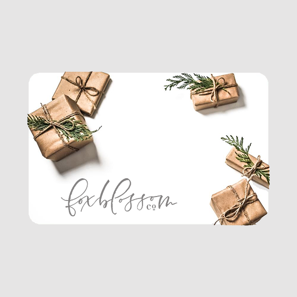 White gift card with script "Foxblossom co" in lower left corner and design of brown paper wrapped presents with evergreen branches.
